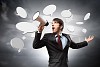 young businessman in black suit screaming into megaphone