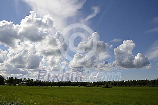Clouds above green field