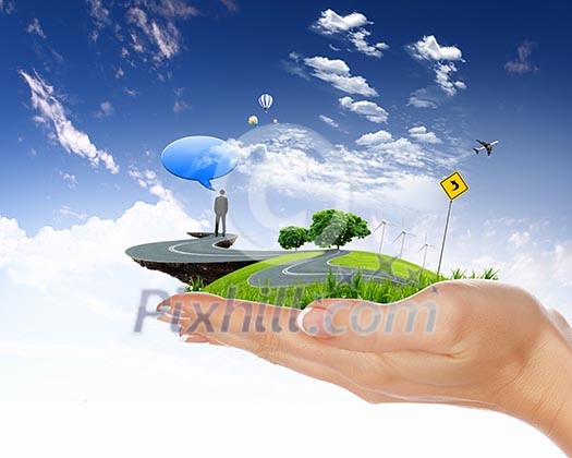 human hand holding a city on green grass hill