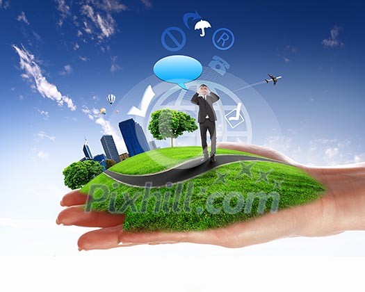 human hand holding a city on green grass hill