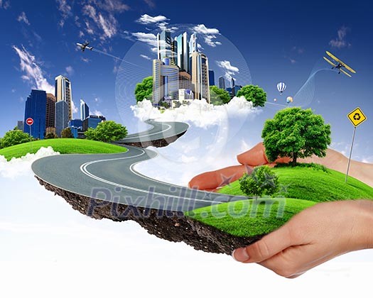 human hand holding a city on green grass hill