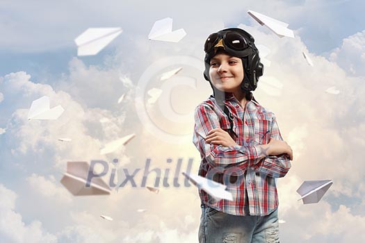 Image of little boy in pilots helmet with paper airplanes in background Image of little boy in pilots helmet with paper airplanes in background