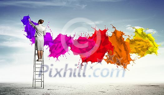 Young woman standing on ladder drawing splashes with finger Young woman standing on ladder drawing splashes with finger