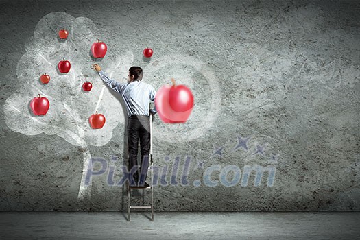 Businessman on ladder pointing at illustrated apple tree Businessman on ladder pointing at illustrated apple tree
