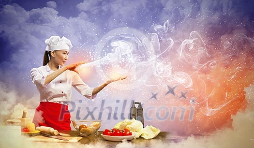 Asian female cooking with magic against color background