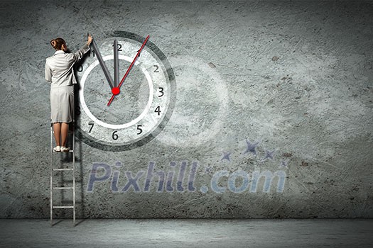 Businesswoman standing on ladder moving hands of clock