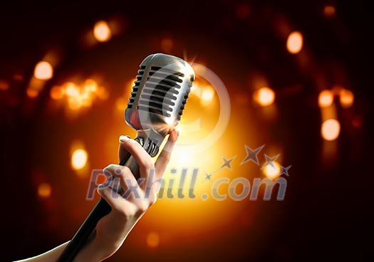 Female hand holding a single retro microphone against colourful background Female hand holding a single retro microphone against colourful background