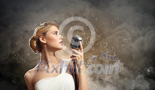 Image of female blonde singer holding microphone against smoke background Image of female blonde singer holding microphone against smoke background