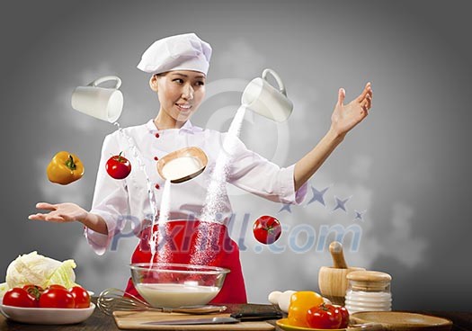 Asian female cooking with magic against color background