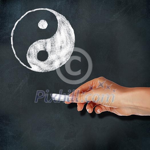 School blackboard and hand with chalk drawing yin-yang symbol School blackboard and hand with chalk drawing yin-yang symbol