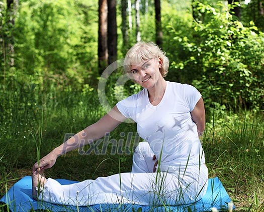 An elderly woman practices yoga in nature. The symbol of healthy lifestyle