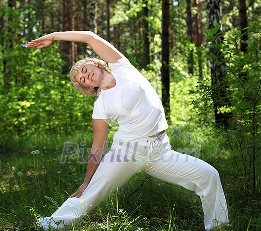 An elderly woman practices yoga in nature. The symbol of healthy lifestyle