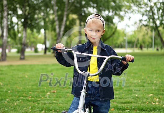 Happy smiling boy on a bicycle in the green park