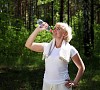 An elderly woman after exercising in the forest holding a bottle of water