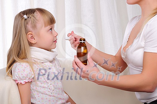 Little girl drinking cough syrup with a small spoon from the hands of moms