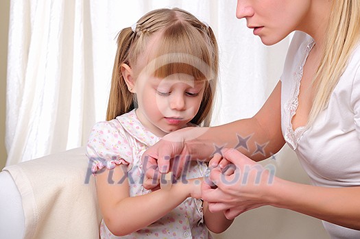 Mom puts her baby daughter plaster on the sore arm Mom puts her baby daughter plaster on the sore arm