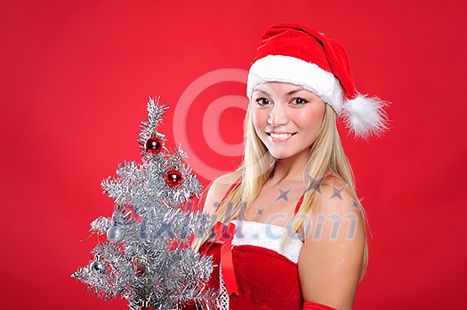 Portrait of a young charming girl dressed as Santa with a Christmas tree. Happy New Year!