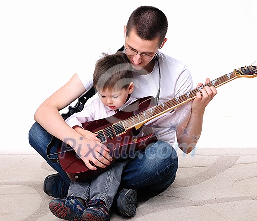 A young father teaches his young son to play guitar A young father teaches his young son to play guitar