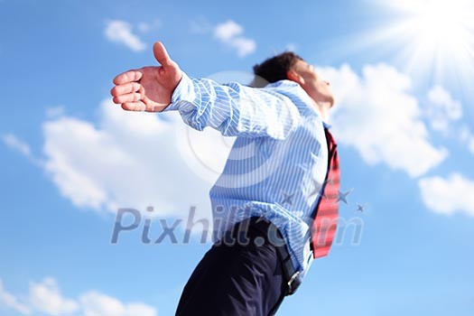young business man in a blue shirt and red tie against the blue sky. a symbol of leadership, success and freedom. young business man in a blue shirt and red tie against the blue sky. a symbol of leadership, success and freedom.