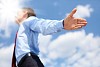 young business man in a blue shirt and red tie against the blue sky. a symbol of leadership, success and freedom.