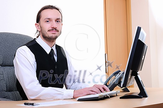 A young business man working on the computer in the office.