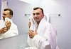 young man in bathroom wearing white bathrobe