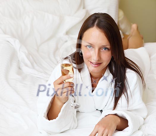 young woman with glass of champagne wearing bathrobe
