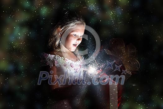 Child opening a magic gift box with lights and shining around