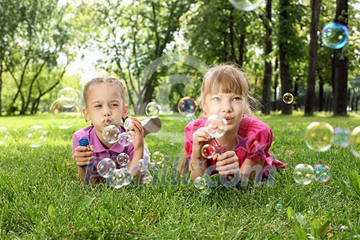 Little girls in the summer park blowing bubbles Little girls in the summer park blowing bubbles