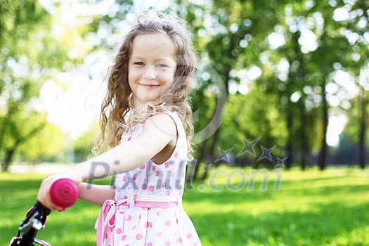 Little happy girl having fun in green summer park