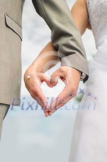 Hands of a bride and groom shaped as a heart