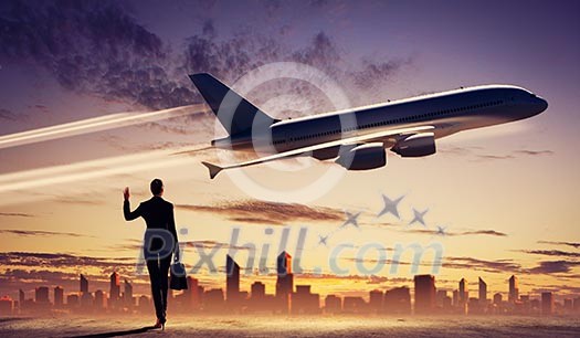 Image of business woman holding suitcase looking at airplane in sky