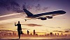 Image of business woman holding suitcase looking at airplane in sky