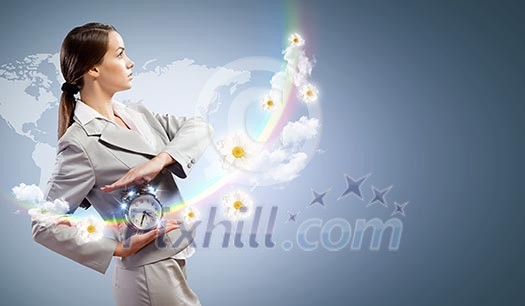 Image of young businesswoman holding alarmclock against illustration background