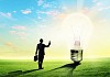 Image of businessman looking at light bulb. Green energy concept