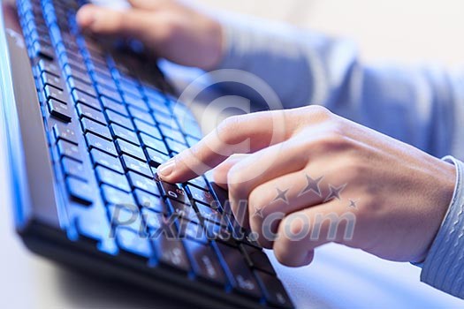 Click! Hands of a man on a keyboard with blue backlighting.