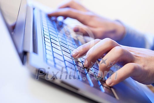 Click! Hands of a man on a keyboard with blue backlighting.