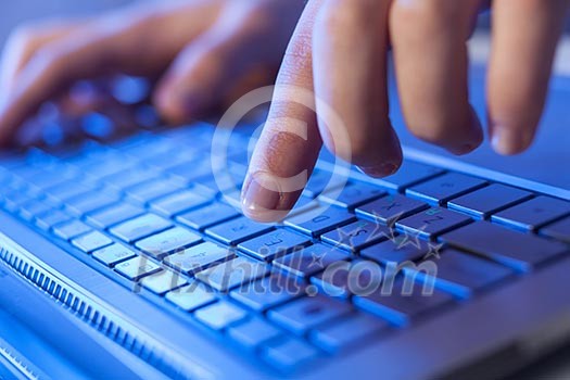Click! Hands of a man on a keyboard with blue backlighting. Click! Hands of a man on a keyboard with blue backlighting.