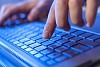 Click! Hands of a man on a keyboard with blue backlighting.