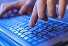 Click! Hands of a man on a keyboard with blue backlighting.