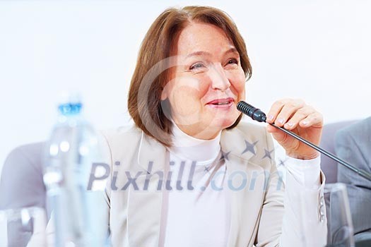 Image of businesswoman at business meeting speakig in microphone