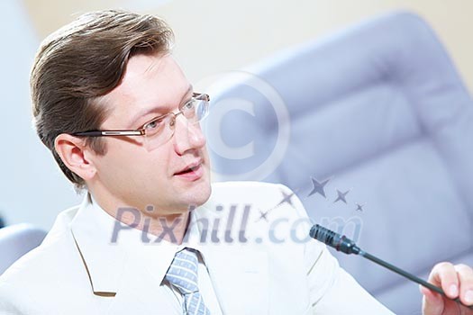 Image of young businessman sitting at table at business meeting