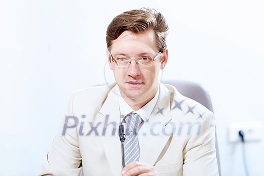 Image of young businessman sitting at table at business meeting