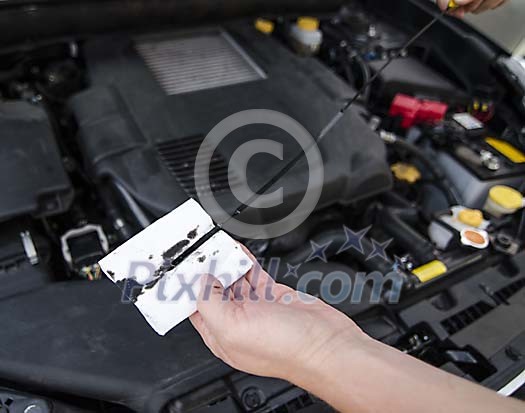 A mechanic checking the level of motor oil in the engine A mechanic checking the level of motor oil in the engine
