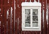 A window on a red house covered in frost and snow