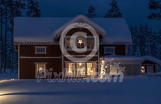 A red house at night with snow and christmas lights in the windows