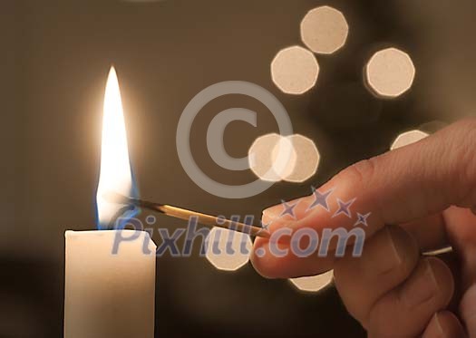 Hand lighting a candle with a match