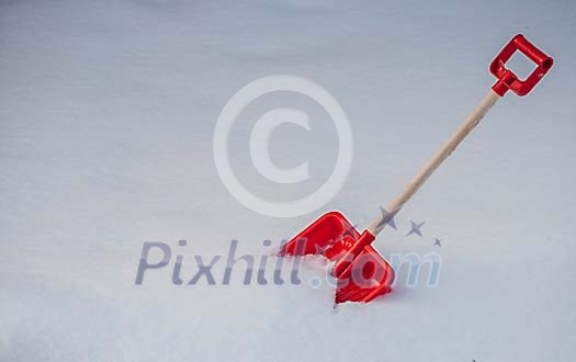 A red snow shovel in the snow