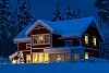 A red wooden house covered with snow. Christmas lights in tree