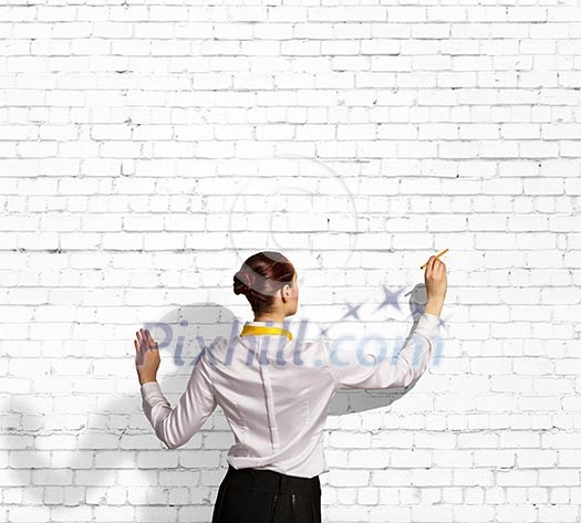 Businesswoman standing with back drawing on blank wall Businesswoman standing with back drawing on blank wall